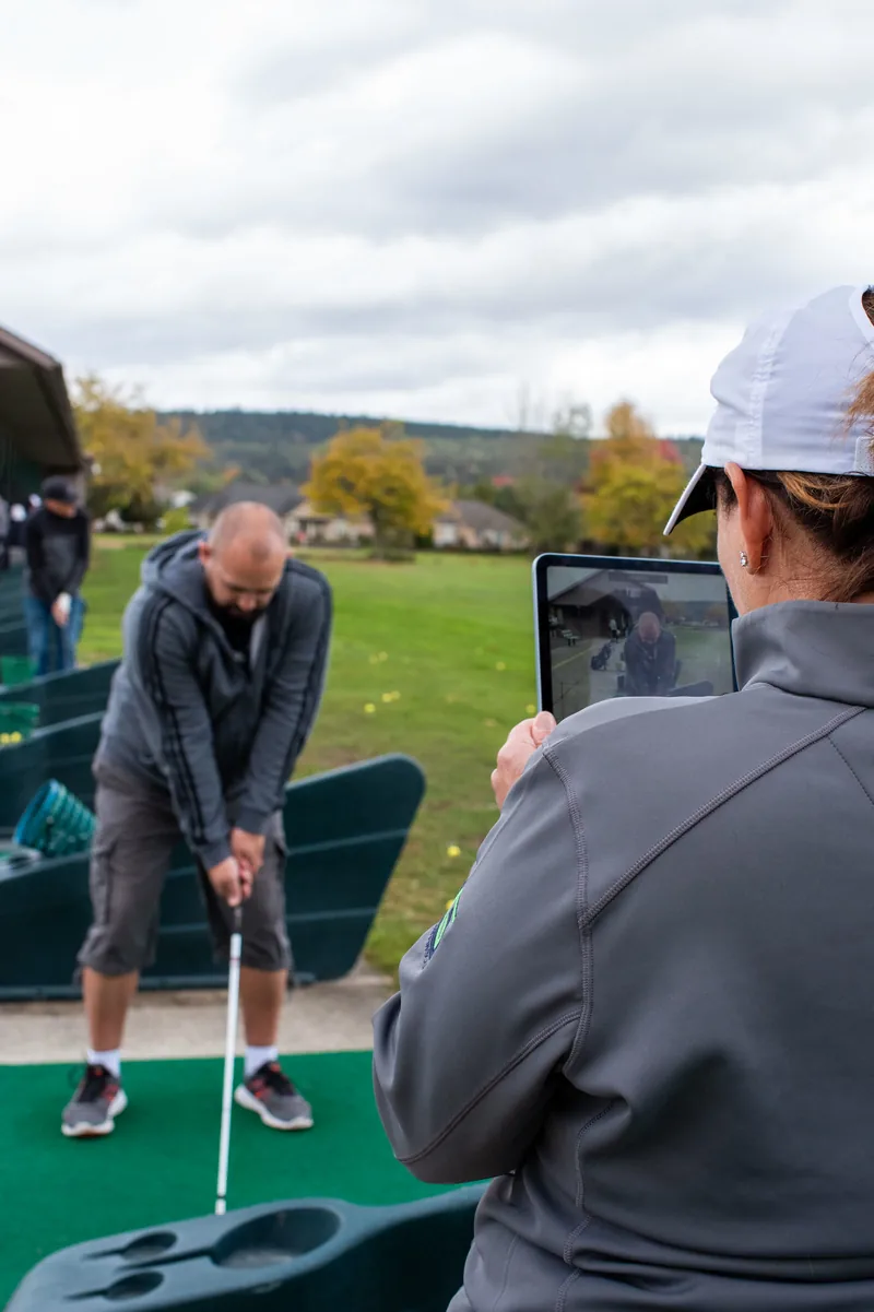 A Team Griffin coach records a golfer at the driving range